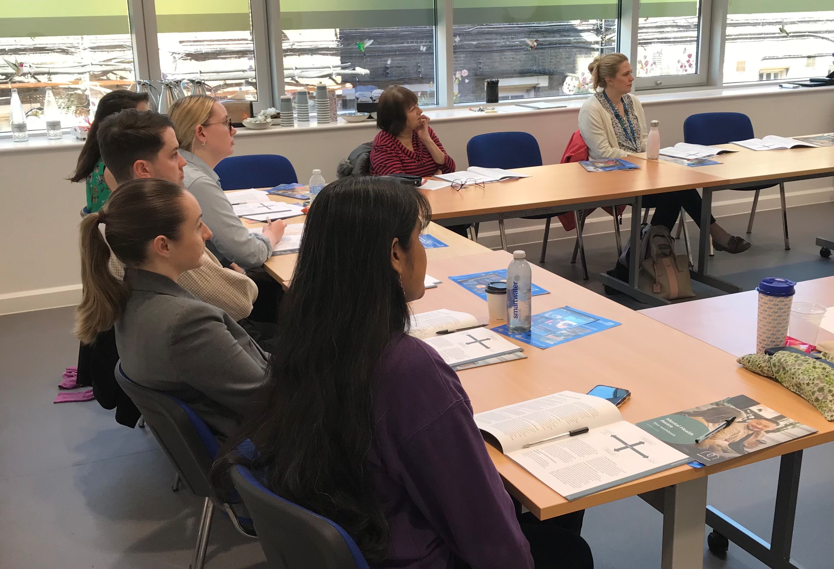 An over the shoulder photo that shows participants in training paying attention in a meeting room.