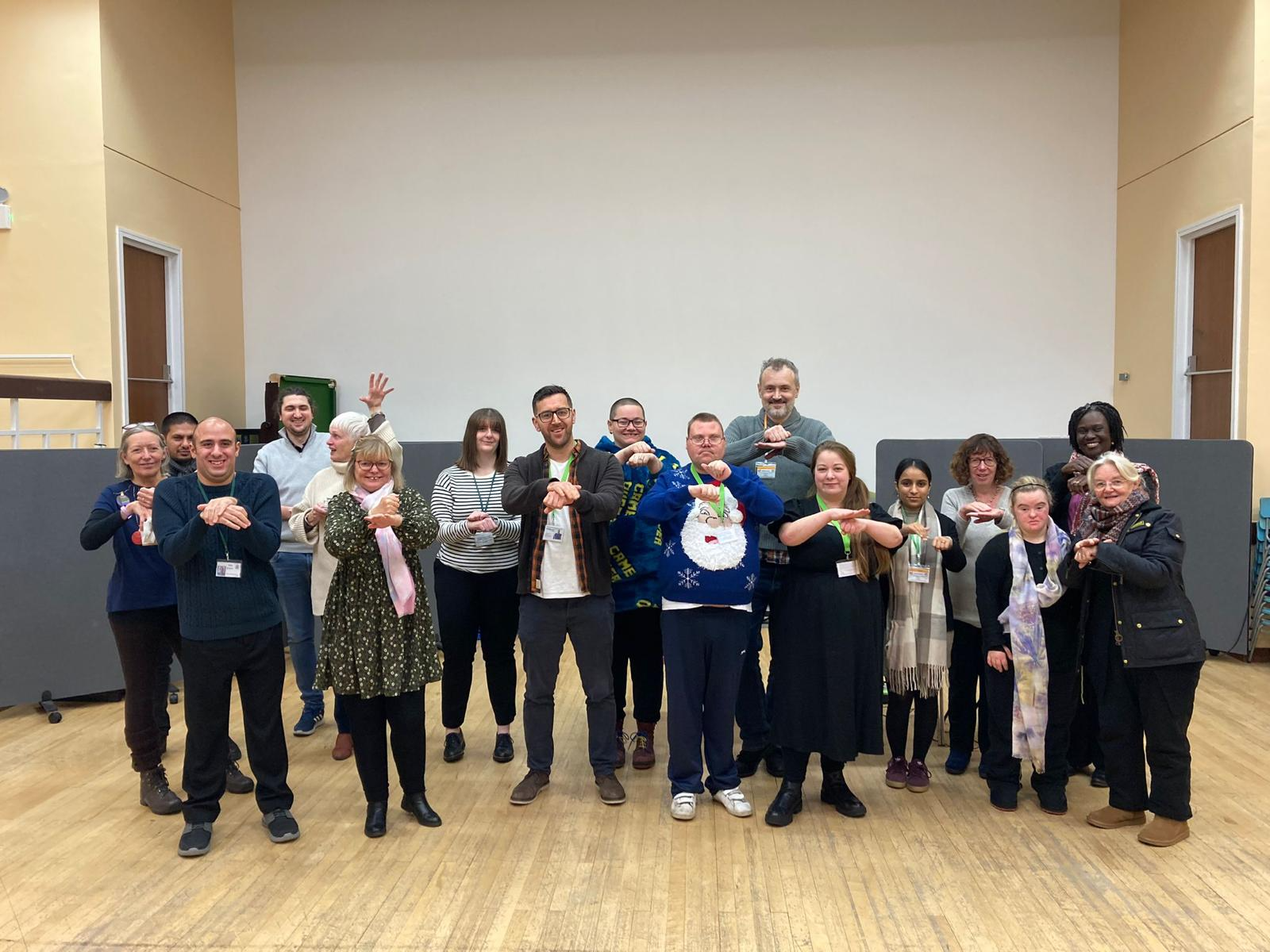 A photo of a group of people, they are stood together posing for the photo with the arms outstretched and hands over the top of each other.