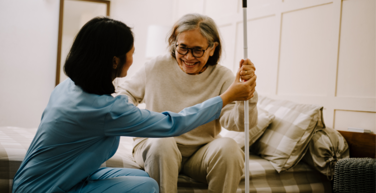 A photo of an elderly woman in her home as she helped to stand by a nurse.