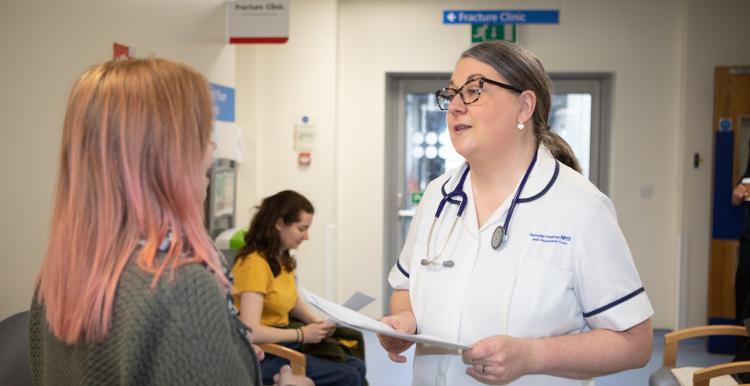 A photo of a woman talking to a medical professional in a hospital waiting room
