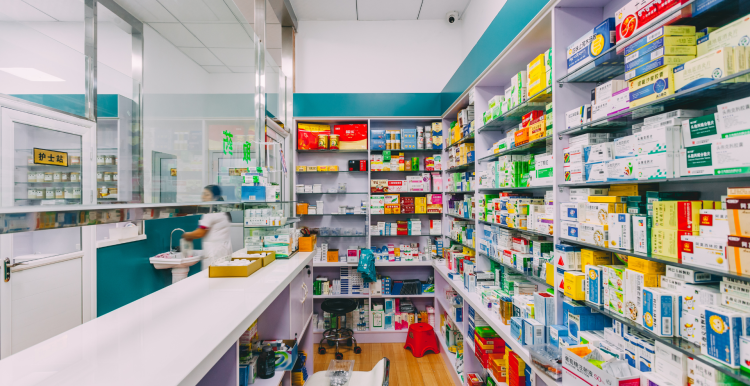 A photo of a pharmacy showing shelves of medicine behind a counter