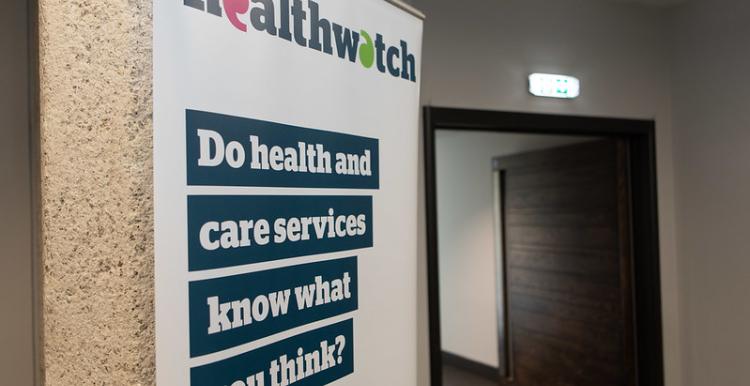 A photo of a pop-up Healthwatch banner. The banner has bold text that reads 'Do health and care services know what you think?'