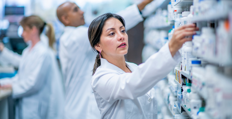 A photo of a woman in a pharmacy taking medicine from a shelf