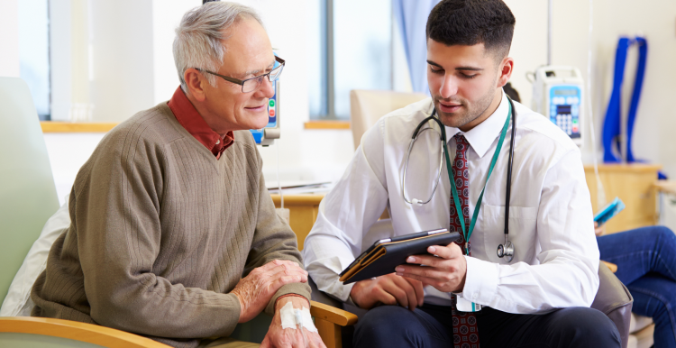 A photo of a clinician showing an older patient something on a tablet