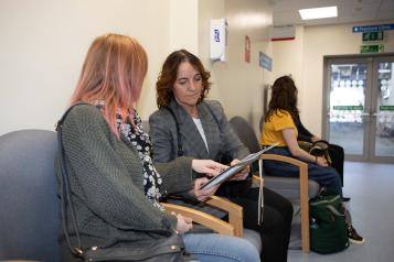 A photo of two women reviewing documents in a waiting room
