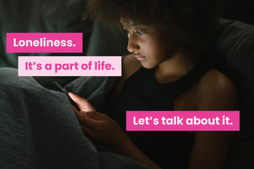 A photo of a young person on their own in a dark room. Text reads 'loneliness. it's a part of life. let's talk about it.'