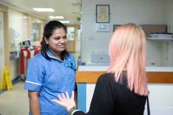 A photo of a woman talking to a nurse at a hospital reception