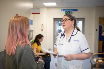 A photo of a woman talking to a medical professional in a hospital waiting room