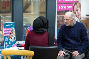 A photo of two people sat at an information desk
