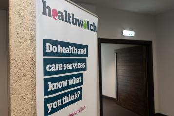 A photo of a pop-up Healthwatch banner. The banner has bold text that reads 'Do health and care services know what you think?'