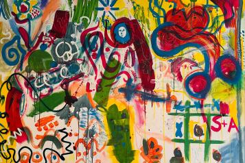 A photo of a canvas that has been expressively painted with bright colours and shapes.