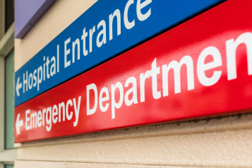 A photo of signs pointing to a hospital entrance and emergency department