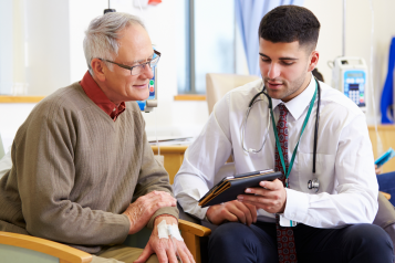 A photo of a clinician showing an older patient something on a tablet
