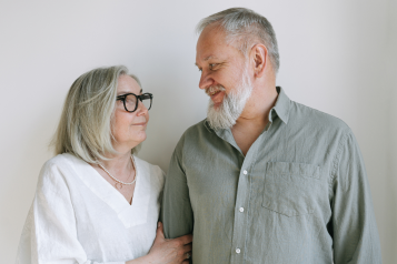 a photo of a mature couple stood side by side looking at each other.