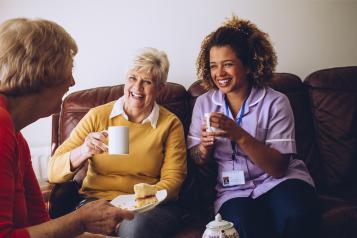 Ladies laughing and having tea and cake with a Dementia friendly carer