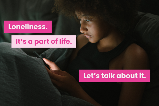 A photo of a young person on their own in a dark room. Text reads 'loneliness. it's a part of life. let's talk about it.'