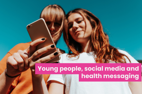 A photo of two young women looking at something on a phone together. Bold text across the image reads 'Young people, social media and health messaging'