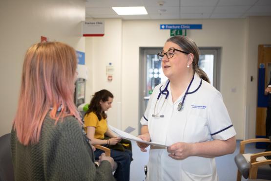 A photo of a woman talking to a medical professional in a hospital waiting room