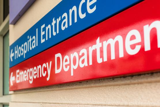 A photo of signs pointing to a hospital entrance and emergency department