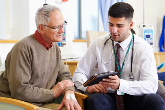 A photo of a clinician showing an older patient something on a tablet