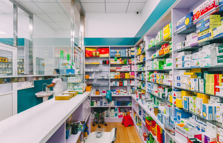 A photo of a pharmacy showing shelves of medicine behind a counter