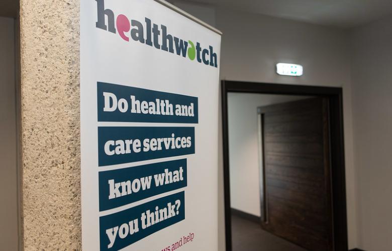 A photo of a pop-up Healthwatch banner. The banner has bold text that reads 'Do health and care services know what you think?'