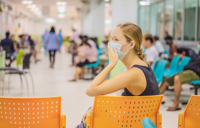 A photo of a woman in a busy hospital waiting room, she is wearing a face mask.
