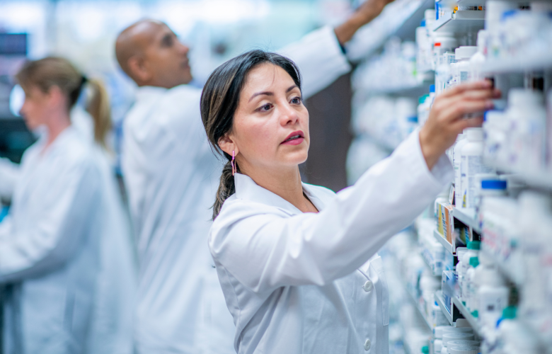A photo of a woman in a pharmacy taking medicine from a shelf